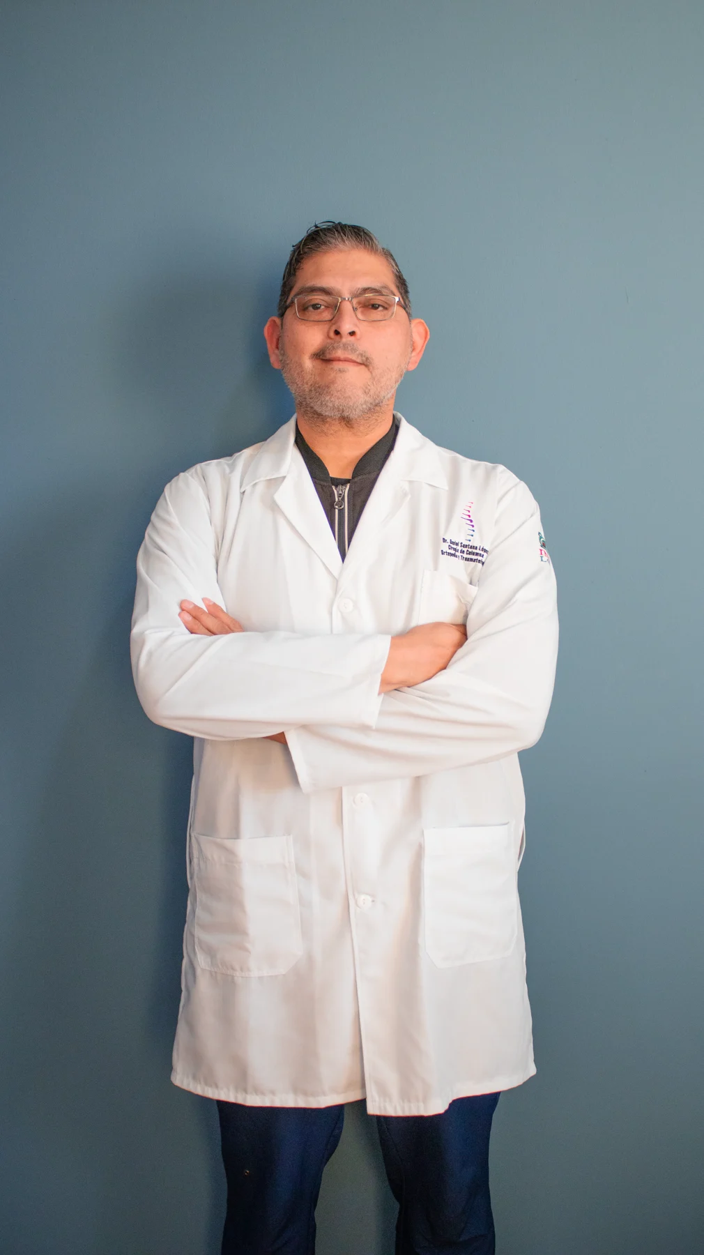 Dr. Daniel Santana López, ortopedista y especialista en columna vertebral, con bata blanca y brazos cruzados